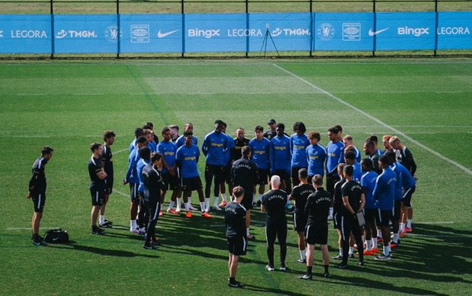 A Chelsea FC squad gathers in a huddle on the training pitch, wearing blue and black kits with BingX, Nike, TMGM, and Legora branding visible on the perimeter boards. The image complements the post by visually reinforcing the message of discipline and teamwork central to the Chelsea-BingX partnership.