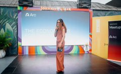 A woman speaks on stage at the Arc Nigeria community event in Lagos, with "JOHNNIE WALKER," "Arc," and "THE ECONOM" visible on the large screen behind her. The setting reflects the post's description of a gathering that brought together developers, founders, and builders from across the Arc ecosystem.