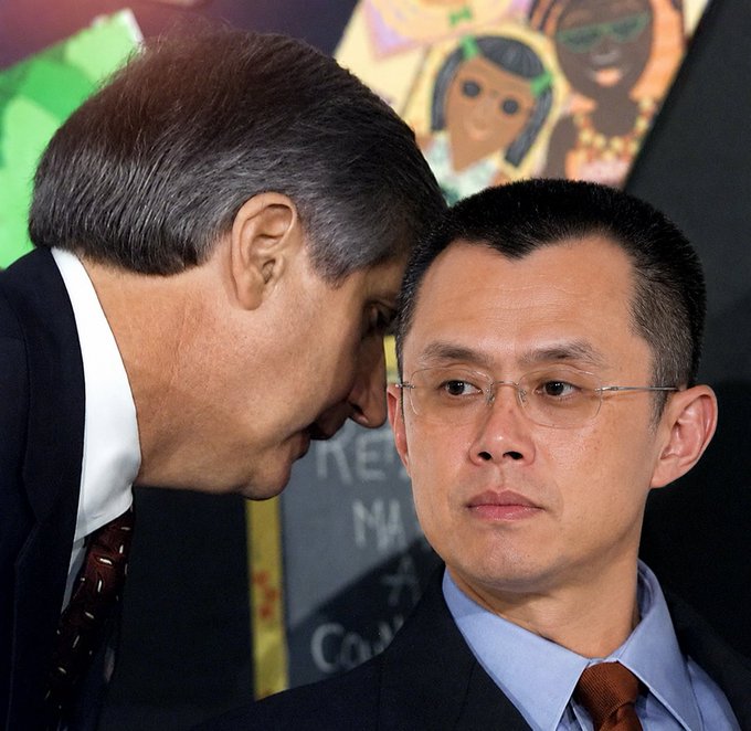 Two men in suits are at a podium, with one leaning in close to whisper to the other while he looks ahead with a serious, slightly taken aback expression. The accompanying caption "that was the wrong coin sir" humorously suggests the whispering man is informing the other of a mistake, perhaps during a coin flip or similar decision-making moment.