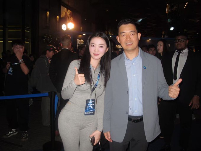 Two people pose with thumbs-up at what appears to be a Geneva event (badge visible), with the man in a gray blazer flashing the gesture alongside his companion. The image humorously connects to the post's "Bear Market Survival Guide" theme, suggesting they're posing with Han at a finance-related gathering.