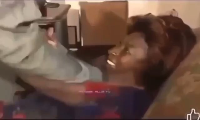 Low-resolution clip showing a child on a couch swinging a white object while an adult sits nearby, with a thumbs-up emoji in the corner.