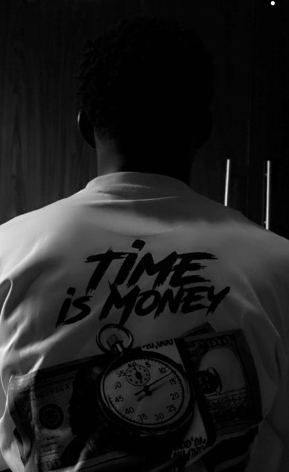 A black-and-white photo of a person seen from behind wearing a white t-shirt with the text 'TIME IS MONEY' and a graphic featuring a stopwatch and US dollar bills.