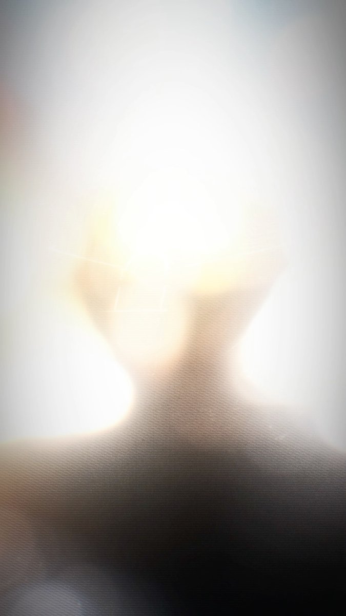 An extremely overexposed photograph showing bright light flares obscuring most details, with what appears to be a wall calendar and shelf faintly visible.