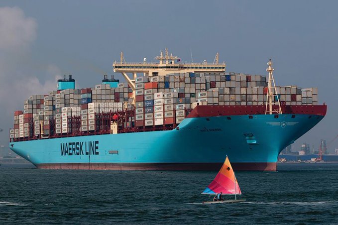 A massive blue "MAERSK LINE" container ship dominates the harbor, dwarfing a small sailboat with a colorful orange and pink sail in the foreground—visually echoing the post's theme of "Contribution Campaigns" by contrasting a giant, established entity with a smaller, active newcomer making its mark on the water.
