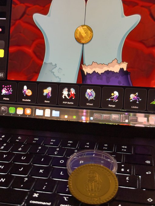 A photo of a laptop screen showing what appears to be a gambling game featuring Patrick Star, with various minigame options like Plinko, Roulette, and Limbo; a physical gold coin with '1 MILLION PESO' rests on the keyboard.