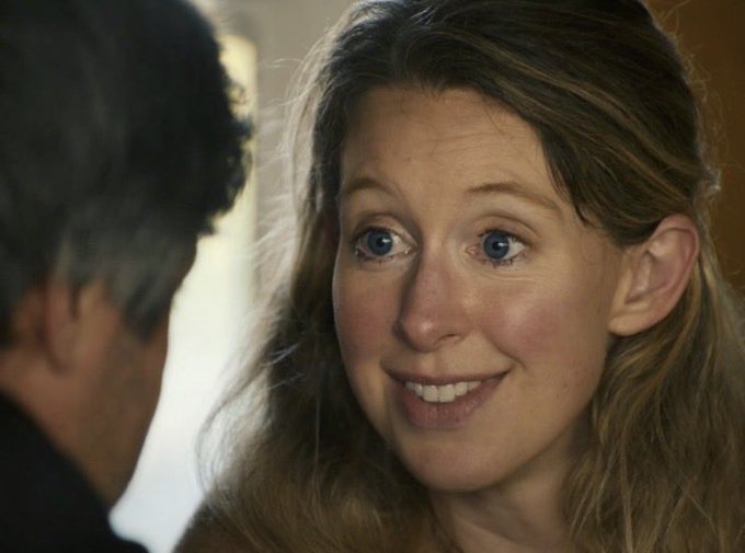 A close-up film still shows a smiling woman looking toward a man in the foreground.