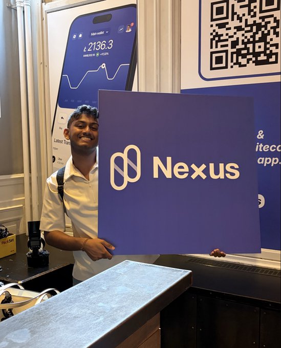 A man at what appears to be a conference booth holds a large purple "Nexus" sign, smiling beside a display showing a wallet interface with "₺ 2136.3" and a Litecoin wallet screen, illustrating the team's presence at a tech event as they promote their Litecoin wallet app.