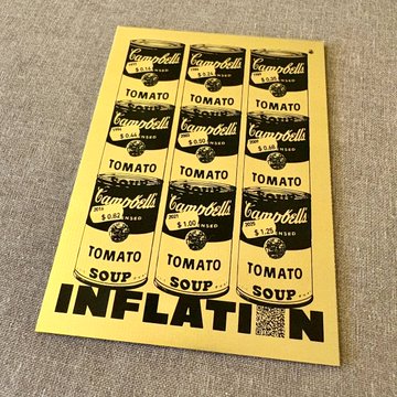 The image features an art piece that is a gold card with black text and images of soup cans, specifically Campbell's Tomato Soup Inflation Soup canisters. The text on the card reads "INFLATION SOUP" and "Gold", while the image shows multiple soup canisters in various sizes and colors. The post also includes a code "btcprague" that might be related to an event or artist.