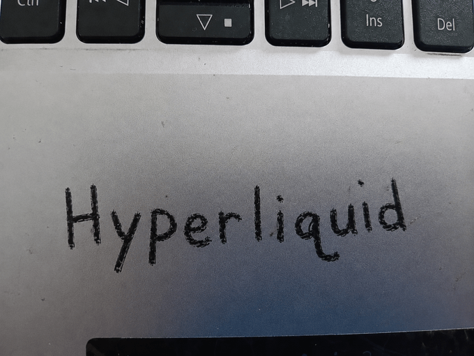Handwritten text 'Hyperliquid' on paper placed on a laptop keyboard.