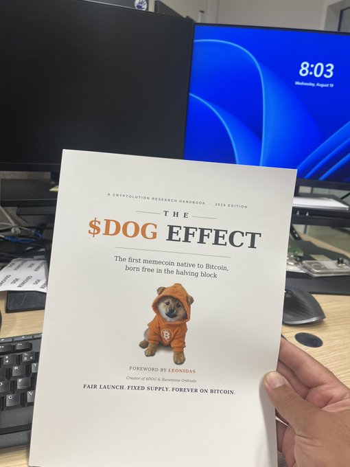 A hand holds up a copy of "The $DOG Effect," a cryptolution research handbook described as 'The first memecoin native to Bitcoin, born free in the halving block,' featuring a Shiba Inu puppy in an orange hoodie on the cover.