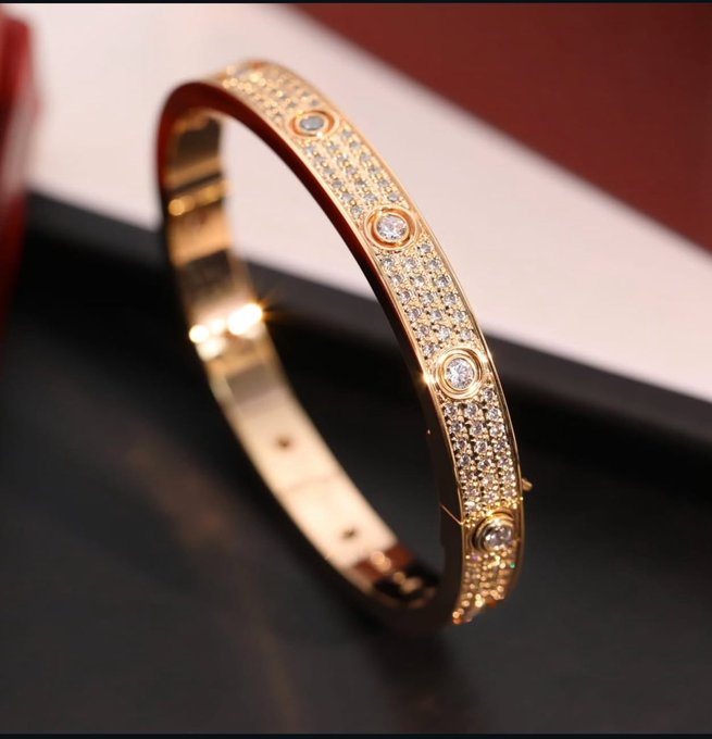 The image features a gold bracelet with diamonds, placed on a black surface. The bracelet has a shiny appearance due to its metallic sheen and the presence of the diamonds. The background appears to be a white wall or a red tablecloth, which contrasts nicely with the bracelet's color. The text "Good morning Web3 Searching for my daily bread" is written in the image, possibly indicating that someone is browsing the internet while wearing the bracelet.