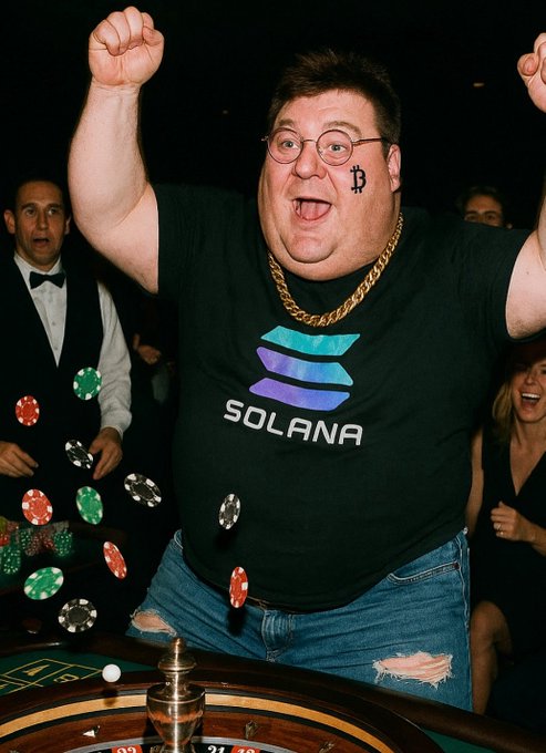 A man in a black Solana-branded t-shirt and gold chain excitedly waves his arms while standing at a casino roulette table, with poker chips flying through the air and a shocked dealer in the background.