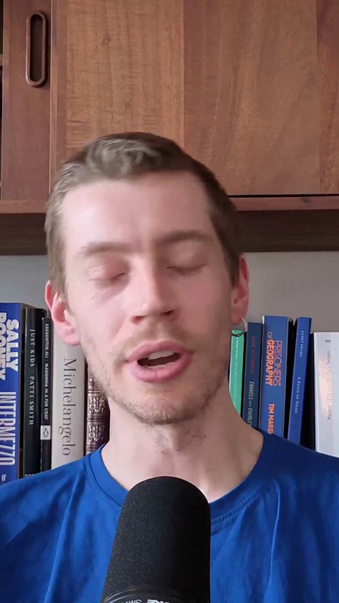 The image features a man wearing a blue shirt who appears to be singing into a microphone or speaking into an earpiece. The background of the image shows a bookshelf filled with various books, suggesting that he might be at a bookstore or a library. The caption provided in the image reads "While the perps obsession continues, @solana has been the industry'S premier spot venue for over a year. Faster than Binance, better execution than Coinbase. Here'S why the real story isn'". This implies that the man's singing might be related to a song or an event happening at @solana, and it could potentially be about Bitcoin or cryptocurrency news.