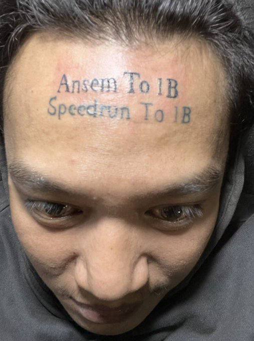A close-up photo shows a man with the words "Ansem To 1B / Speedrun To 1B" tattooed across his forehead in two lines, illustrating the post's reference to someone permanently inking their belief in the meme coin $ANSEM reaching a $1 billion market cap, despite not actually holding any of the token.