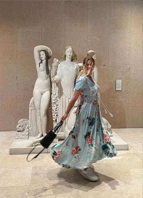 A woman twirls playfully in a flowing light-blue floral dress in front of classical white marble sculptures at what appears to be the Museu Calouste Gulbenkian in Lisbon, marking the perfect cultural finale to a packed Onchain Builders Week filled with eight events, one hosted gathering, and cheering on friends at ETHGlobal.