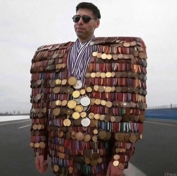 A man wearing sunglasses and an elaborate suit jacket completely covered in hundreds of coins, medals, and trinkets, standing on an empty racetrack with a Grok watermark in the corner.