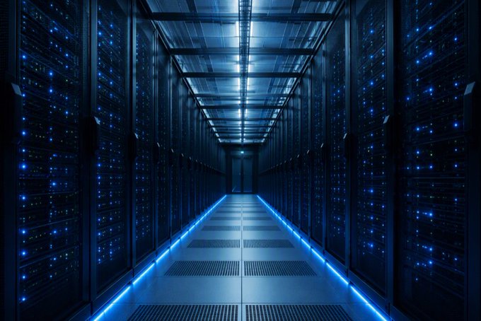 An illuminated server room corridor features rows of server racks with glowing blue lights, creating a high-tech, futuristic atmosphere.