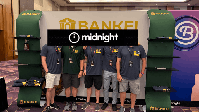 A group of people stand in front of a "BANKFI" banner and two green "BANKFI" display shelves, with a "midnight" logo watermark overlaid in the center.