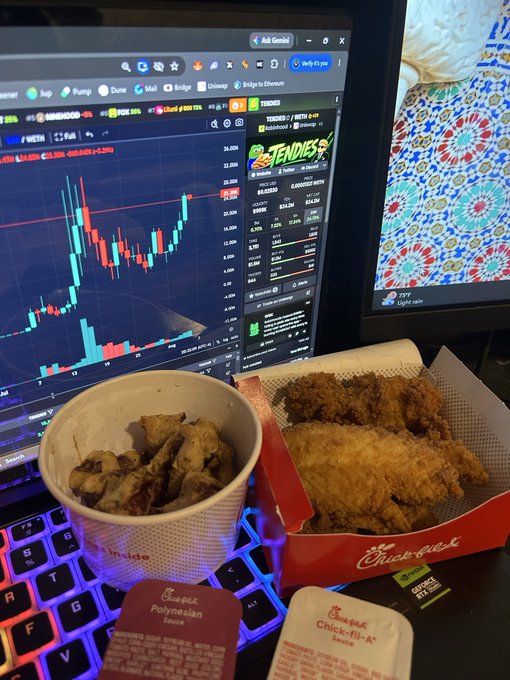 A Chick-fil-A meal with fried chicken and a side sits on a keyboard in front of a laptop displaying cryptocurrency charts, including 'THE TENDIES' token.