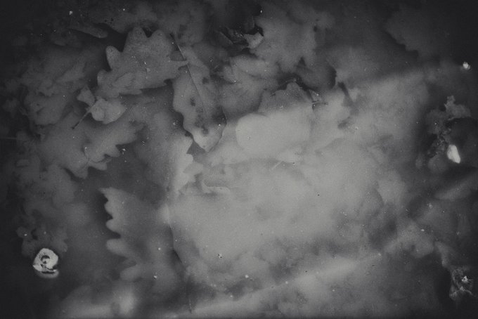 An abstract black and white image resembling swirling clouds, smoke, or a fluid ink wash pattern.