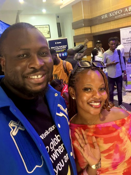Two smiling attendees pose for a selfie at the Sir Kofo Abayomi Auditorium during Web3 Lagos Con, with the man wearing a blue jacket and the woman in a vibrant orange and red off-shoulder top, capturing the energetic networking atmosphere the post describes.