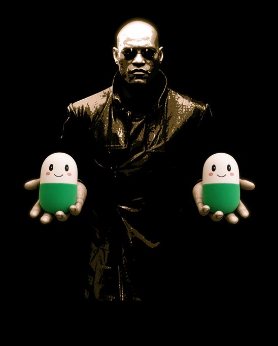 A dramatic dark-toned image of a bald man in a leather coat wearing sunglasses, holding out two green and white pill-shaped figures with smiling faces in each hand.