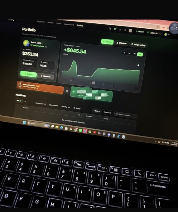 A photograph of a laptop screen displaying a portfolio dashboard with a balance of '$253.54' and profit/loss of '+$645.54', positioned above a black keyboard.