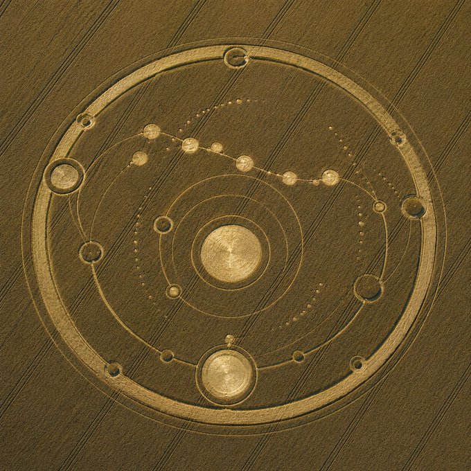 A circular geometric design resembling a futuristic or astrological symbol with concentric rings and nodes on a textured brown background.