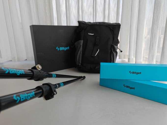 A black backpack with the "Bitget" logo sits between a branded tripod and a teal box, both also displaying the "Bitget" logo.