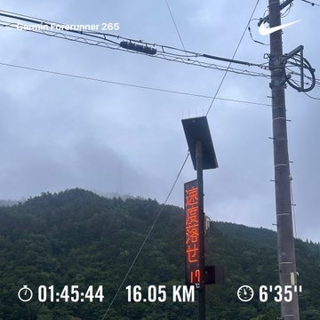 A cloudy sky frames a utility pole, power lines, and an LED display in a rural area, with a forest in the background. Overlay text shows "Pacer Forerunner 265" along with metrics "01:45:44 16.05 KM 6'35"", matching the post's reference to a 16 km morning run tracked during a STEPN challenge.