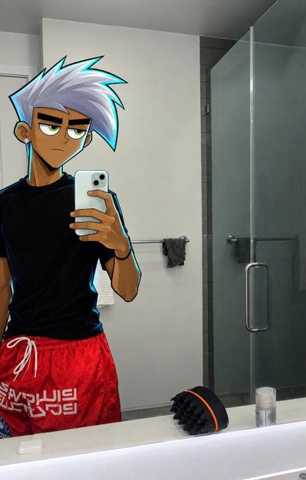 A person taking a mirror selfie in a bathroom wearing a black t-shirt and red shorts, with a cartoon anime-style character overlay featuring spiky white hair.