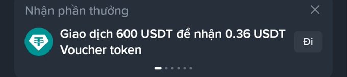 A Vietnamese-language notification popup stating 'Nhận phần thưởng' (Receive reward) with a prompt to trade 600 USDT to receive 0.36 USDT Voucher token.