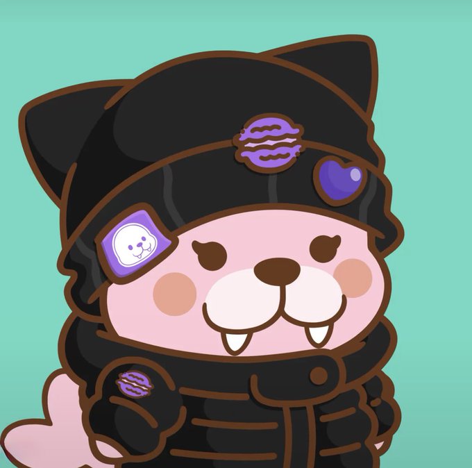 A cartoon illustration of a pink cat-like character wearing a black hooded outfit with cat ears, a purple macaron emblem, and a heart patch on a teal background.