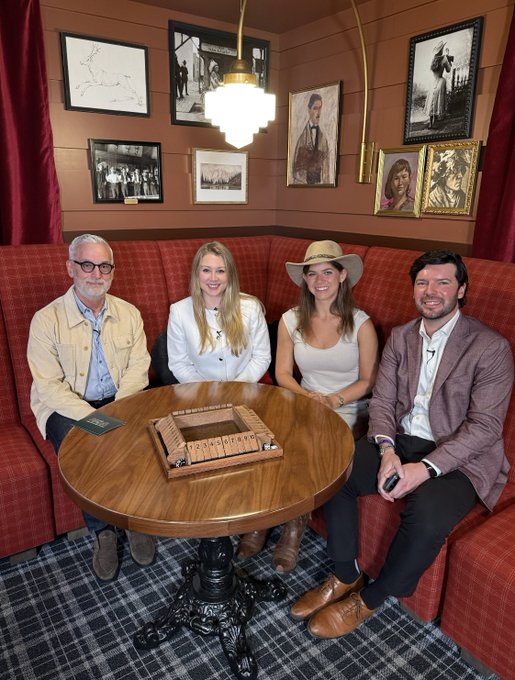 Four people sit around a wooden table with a cribbage board, posing for a photo in a room decorated with framed artwork and a hanging lamp, following their discussion at the SALT Conference Wyoming Symposium with Ripple's Chief Legal Officer Stuart Alderoty about Ripple, XRP, and regulatory developments.