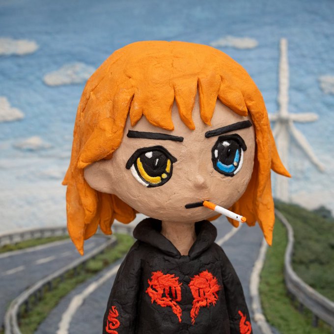 A claymation-style figure of a girl with orange hair, heterochromatic eyes (yellow and blue), and a cigarette, wearing a black hoodie with red graphics, stands before a painted background of a road and wind turbine.