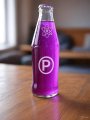 The image features a purple bottle with the letter "P" on it, sitting on top of a wooden table. The text in the image reads "Get some of that Proton pop $METAL XPR", which seems to be related to the purple bottle and possibly a product or promotion involving the Proton pop brand.

The background of the image is blurred, but there appears to be a couch visible behind the wooden table where the bottle is placed.