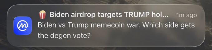 A notification on a mobile device about a popcorn-themed meme coin news: 'Biden airdrop targets TRUMP hol...' from 1m ago, with the preview text 'Biden vs Trump memecoin war. Which side gets the degen vote?'