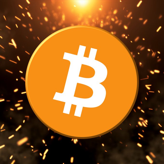 A golden Bitcoin (₿) coin is displayed against a dark background illuminated by fiery sparks and glowing light. The image relates to the post by serving as a visual symbol for cryptocurrency and DeFi discussions, relevant to Cardano founder Charles Hoskinson's comments on the Bitcoin DeFi ecosystem.
