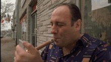 The image shows an older man sitting outside a building, smoking a cigar while looking at his phone. The surrounding area appears to be a street with trees nearby. There are also other people present in the scene, but they are not the main focus of the image. The caption reads "Congrats @thebeaksart $60 We distributed a total of 35 GTD spots in ZAX. That means we helped the ZAX community make over $15k from just one collection." This post seems to be related to an online auction or sale, possibly for a rare item like a cigar, as it mentions that "we will continue to win together."
