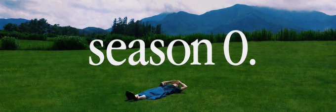 An aesthetic image showing a person lying in a lush green field with mountains in the background, overlaid with the text 'season 0.'