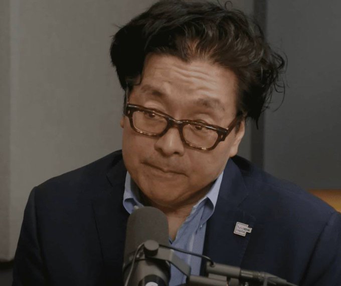 A man in a navy blazer and blue shirt with thick-rimmed glasses is speaking into a microphone, appearing in what looks like a podcast or interview setting, while the accompanying post demands a "$100M plus cook" for the Ethereum trenches.