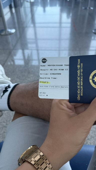 A person holding a boarding pass for a flight from Ho Chi Minh City to Singapore with a Vietnamese passport visible, with seat 50F.