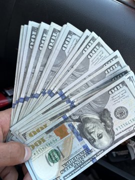 The image shows a person holding up a stack of US dollar bills, with some of them appearing dirty or worn. The person's hand is positioned over the money, emphasizing its importance. The text "Good morning everyone. Finally I was able to grab some sats on this dip. I converted my overtime into sats." suggests that the person has been working hard and is now enjoying their well-deserved break by spending the money on a vacation or other leisure activities.