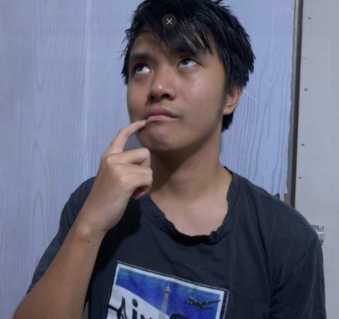 A young man in a black graphic tee rests his finger on his chin while gazing upward with a contemplative expression, perfectly illustrating the thoughtful pondering of how to "ascend" from level 19 mentioned in the caption.