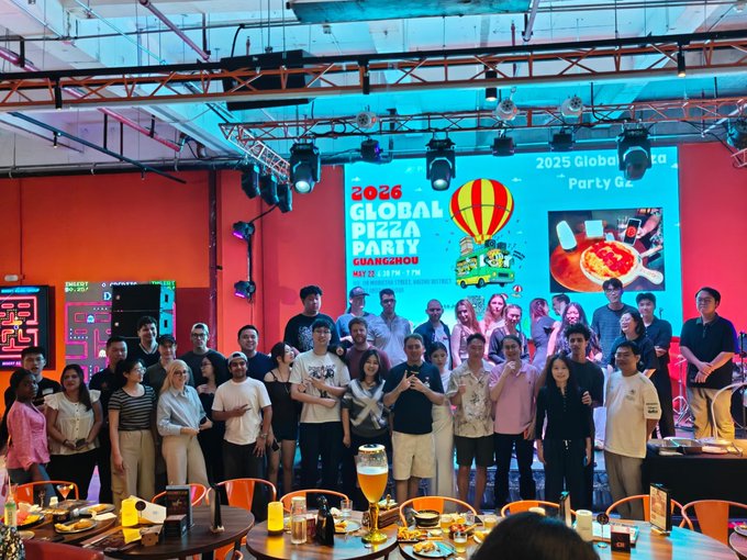A group photo from the '2026 Global Pizza Party Guangzhou' event showing attendees posing in front of a colorful SpongeBob-themed backdrop at what appears to be an entertainment venue.