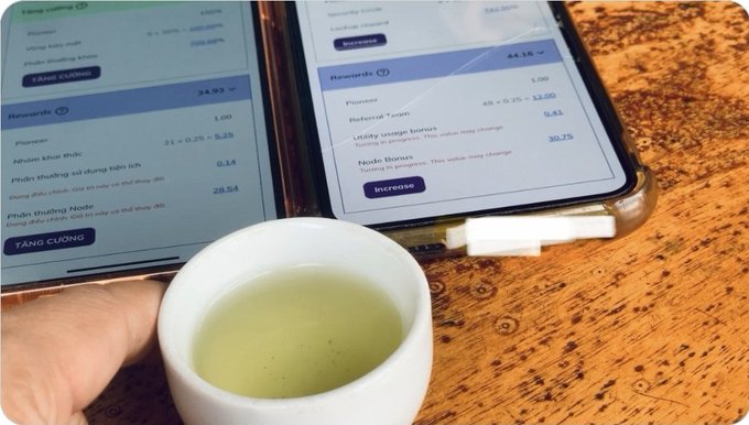 A hand cradles a small cup of green tea alongside two smartphones displaying Pi Network Node Bonus statistics, with one showing a 34.93 bonus and a 28.54 earning rate, while the other displays 54.16 rewards and 30.75 utility usage bonus. The image relates to the post's message about Pi Node reliability rankings, visually emphasizing the importance of monitoring node performance and uptime to secure a trustworthy spot and earn bonuses within the Pi ecosystem.