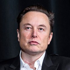A serious-looking man with short brown hair, wearing a dark blazer over a white collared shirt, gazes directly at the camera against a dark background. The image accompanies a post about Elon Musk's prediction that AI will nearly double US GDP growth from 2% to 4% or higher.