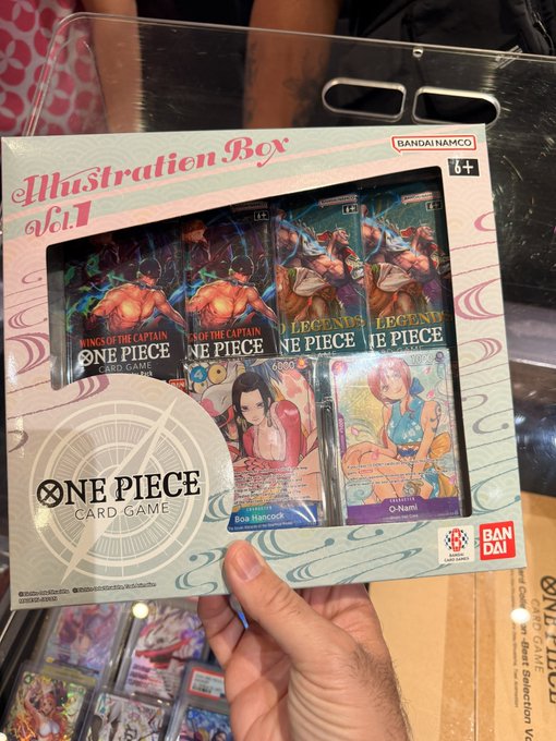 A hand holds a "One Piece Card Game Illustration Box Vol. 1" by Bandai Namco (rated 6+) containing Kings of the Captain booster packs and character cards featuring Boa Hancock and Nami, suggesting the poster is contemplating whether to purchase this collectible card game product.