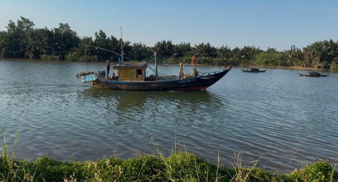 The image features a boat floating on a body of water, surrounded by lush green grass. The boat appears to be an old fishing boat or a small ship with a blue hull. There are two people visible on the boat, possibly fishermen preparing for their next trip out on the water. In addition to the main boat, there is another smaller boat nearby, suggesting that this body of water may serve as a popular spot for recreational activities and fishing. The image also contains text that reads "I like how @XOOBNetwork puts security first → 2FA protection → audit processes → safer user experience so you can actually enjoy Web3 without worrying".