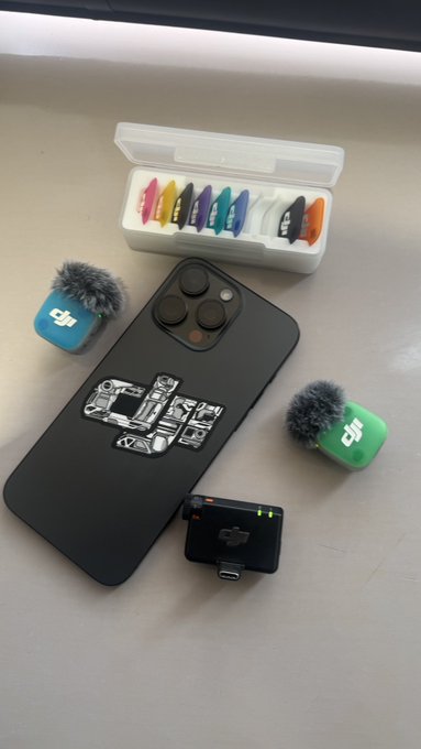 A phone with a DJI mic and colorful mic windshields arranged on top saying "gm" fitting the post.